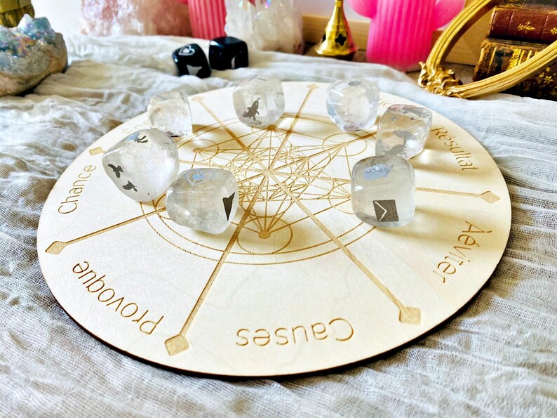 May include: A wooden circular board with a mandala design and eight points. Each point has a word written on it: "Chance", "Provoque", "Causes", "Aeviter", "Resultat",  "Chance", "Provoque", "Causes".  There are eight clear crystal dice with black symbols on them placed on the board.