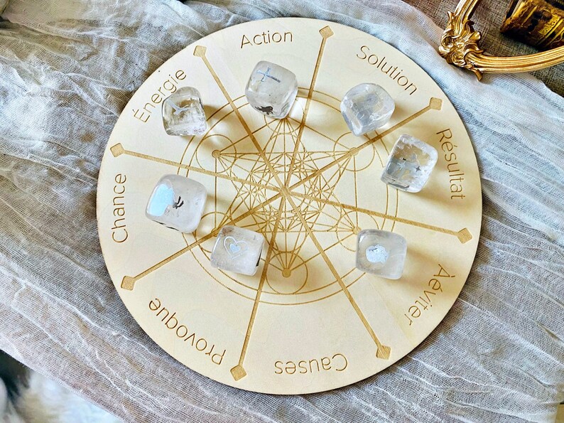 May include: A wooden circular board with a grid pattern and the words "Action", "Solution", "Resultat", "Chance", "Provoque", "Causes", "Avenir", "Energie" printed around the edge. There are eight clear quartz crystals with different symbols inside, placed on the board.