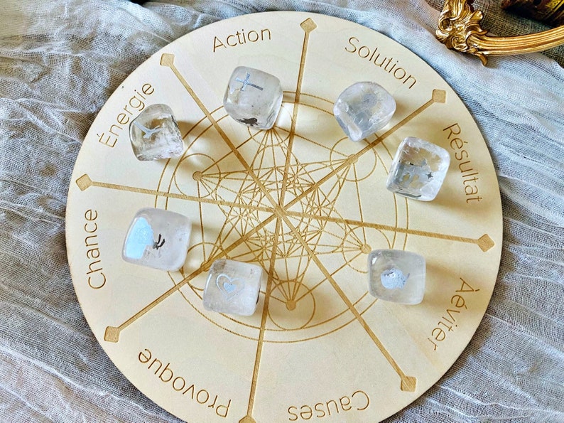 May include: A wooden circular board with a geometric pattern and the words "Action", "Solution", "Resultat", "&Eacute;viter", "Causes", "Provoque", "Chance", "&Eacute;nergie" printed around the edge. There are eight clear quartz crystals with different symbols on each, placed on the board.