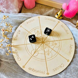 May include: A wooden circular board with a geometric design and eight points labeled with French words: "&Eacute;nergie", "Chance", "Provoque", "Causes", "&Eacute;viter", "R&eacute;sultat", "Solution", and "Action". Two black dice with white symbols are on the board.