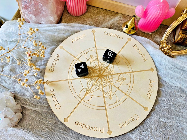 May include: A wooden circular board with a geometric design and eight points labeled with French words: "&Eacute;nergie", "Chance", "Provoque", "Causes", "&Eacute;viter", "R&eacute;sultat", "Solution", and "Action". Two black dice with white symbols are on the board.
