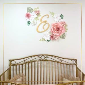 a gold crib with pink roses and a gold monogrammed wall