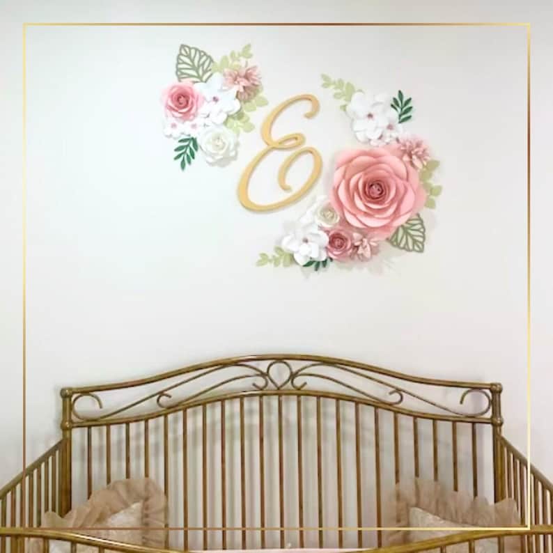 a gold crib with pink roses and a gold monogrammed wall