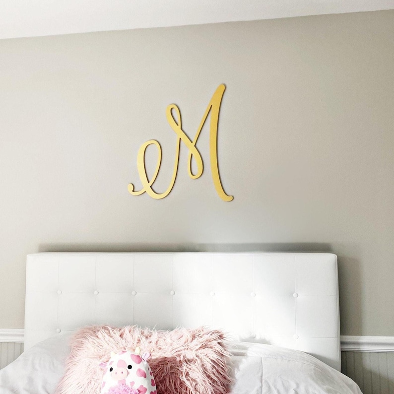 decorative monogram letter M gold wall decor hanging above the bed in a girls bedroom