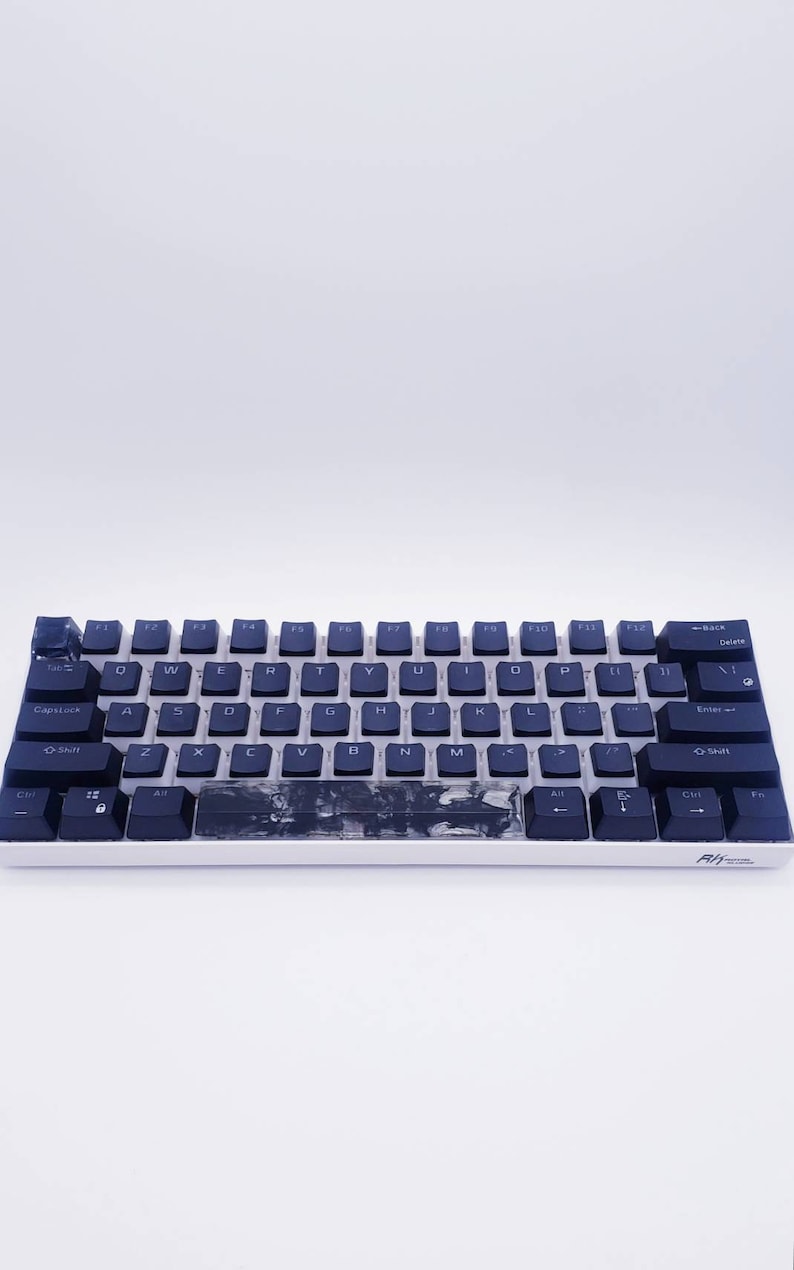 May include: A black and white mechanical keyboard with a black and white marble design on the space bar. The keyboard has a white frame and black keys with white lettering. The keys are labeled with the standard QWERTY layout. The keyboard has a black and white logo on the bottom right corner.