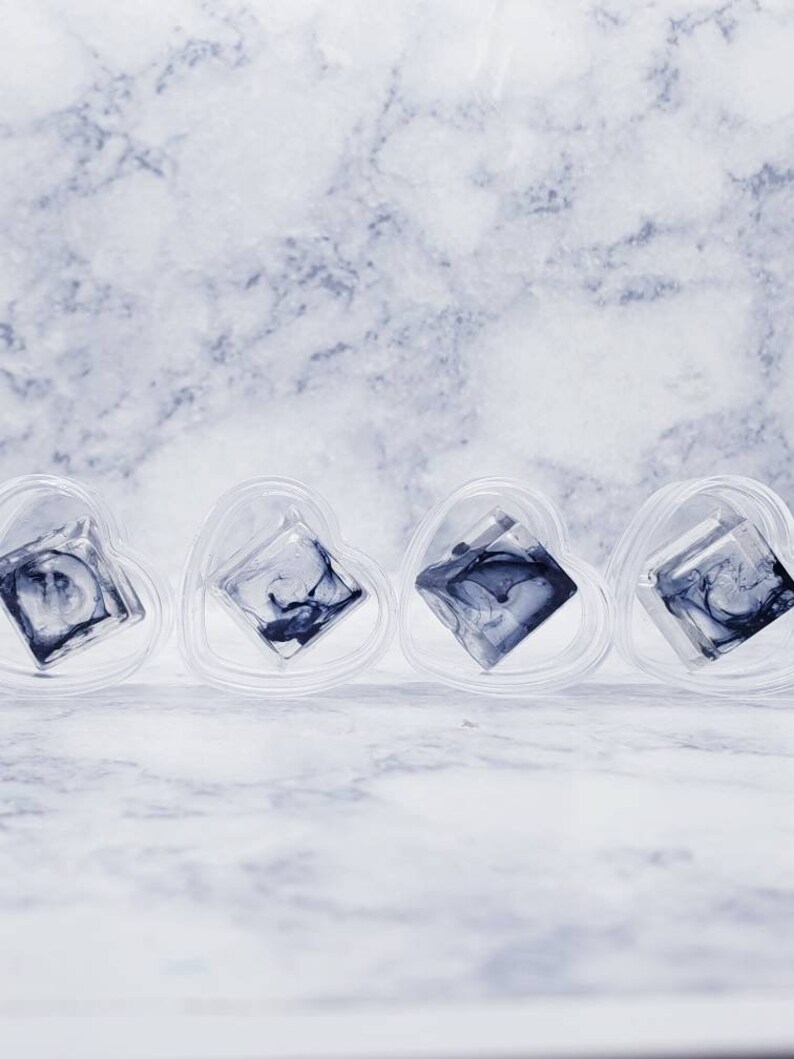 May include: Four clear heart-shaped containers with a black and white marbled design inside each one.