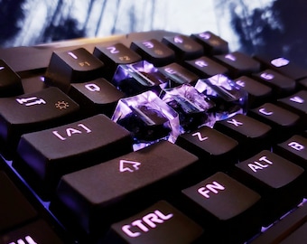 May include: A black keyboard with purple backlighting. The keys are labeled with letters and numbers. The keyboard has a  'CTRL' key, 'FN' key, and 'ALT' key. The keyboard is lit up with purple light.