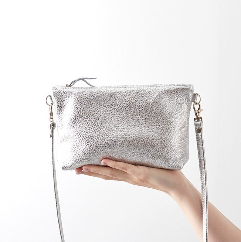 silver leather crossbody bag being held infront of a white background