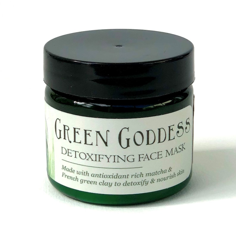 Pu&ograve; includere: Un barattolo verde con un coperchio nero etichettato "GREEN GODDESS DETOXIFYING FACE MASK" con il testo "Made with antioxidant rich matcha & French green clay to detoxify & nourish skin."