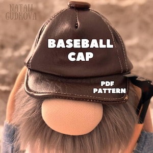 May include: A brown baseball cap with the text "BASEBALL CAP" in white. The cap is part of a gnome doll, with a tan nose and gray beard. The words "PDF PATTERN" are also visible on the cap.