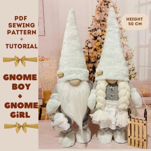 以下が含まれることがあります： 白い生地で作った男の子と女の子のノームの縫製パターンとチュートリアルです。人形は高さ50cmで、白い毛皮の帽子、白いひげ、灰色の服を着ています。女の子の人形は、灰色の星と白い毛皮のトリムが付いた白いドレスを着ています。男の子の人形は、白い毛皮のトリムが付いた灰色のシャツとズボンを着ています。人形はクリスマスツリーの前に立っています。