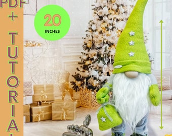 Può includere: Un gnomo di Natale verde e bianco con una lunga barba bianca, che tiene un sacco verde con una stella bianca. Lo gnomo è alto 50,8 cm e si trova davanti a un albero di Natale decorato. L'immagine include il testo "PDF + TUTORIAL" e "20 INCHES".