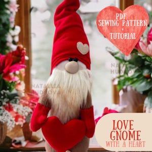 May include: A red and white Valentine's Day gnome holding a red heart. The gnome has a white beard and a red hat with a white heart on it. The gnome is standing in front of a window with a blurry background. The text "LOVE GNOME WITH A HEART" is written on a beige banner below the gnome.