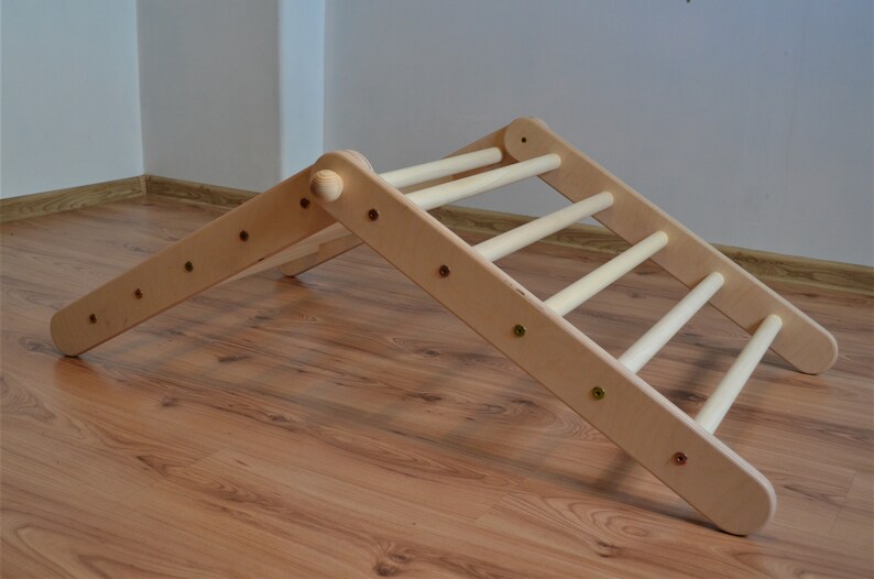 Op de afbeelding: Een houten klimlat met een driehoekig frame. De ladder heeft vijf sporten en is gemaakt van natuurlijk hout.