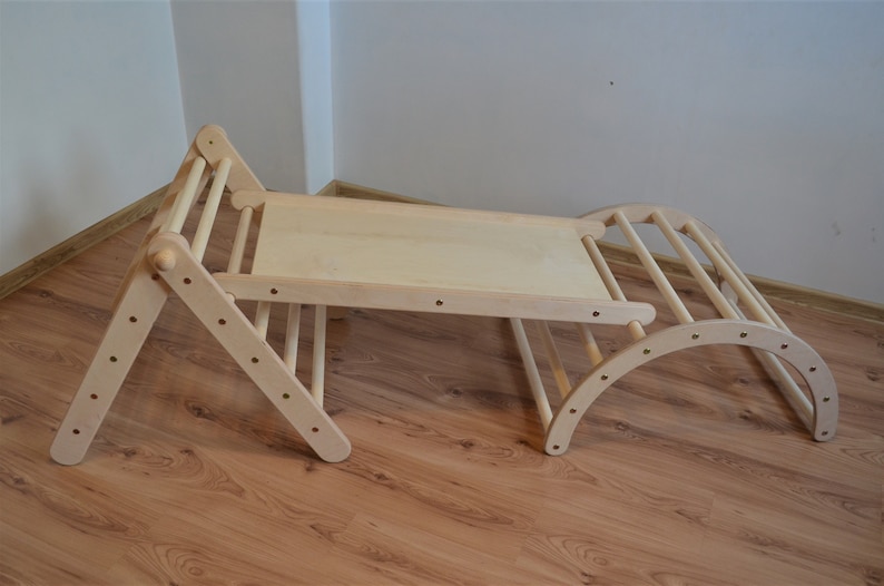 Op de afbeelding: Een houten klimparcours met een glijbaan en een gebogen tunnel. Het frame is gemaakt van natuurlijk hout en heeft een lichtbruine afwerking. De glijbaan is gemaakt van multiplex en heeft een glad oppervlak. De tunnel is gemaakt van hout en heeft een gebogen vorm.