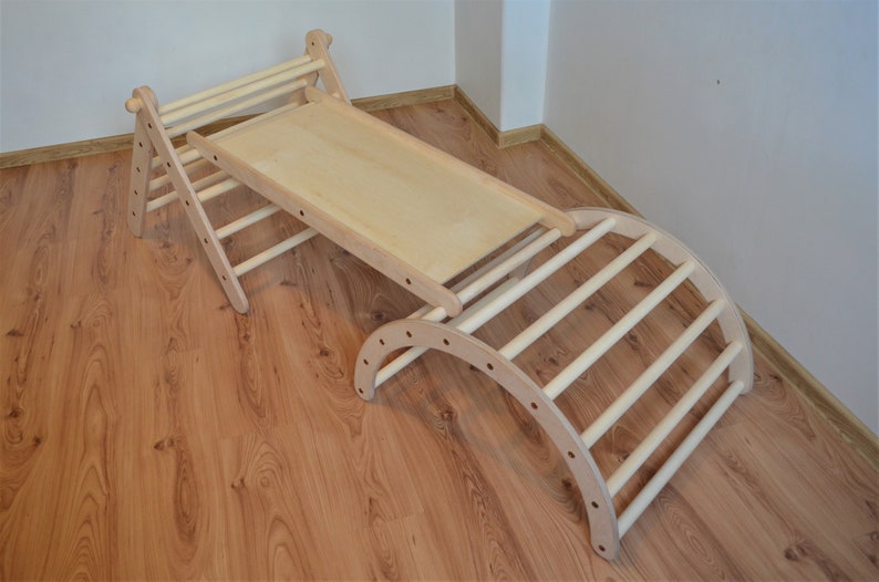 Op de afbeelding: Houten klimparadijs met een glijbaan en een gebogen ladder. Het frame is gemaakt van natuurlijk hout en heeft een lichtbruine afwerking.