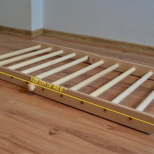 Op de afbeelding: Houten klimlat met 8 sporten, 126 cm lang. De ladder is gemaakt van natuurlijk hout en heeft een lichtbruine kleur.