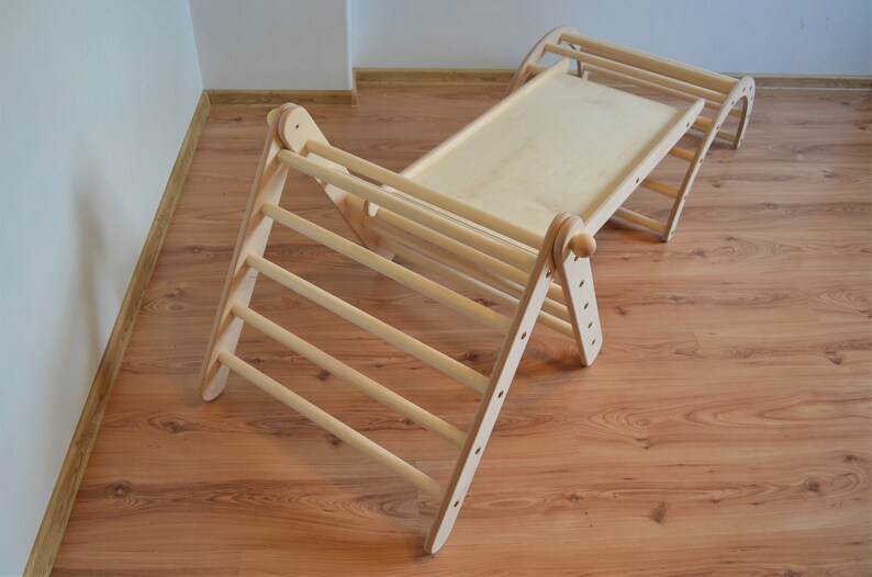 Op de afbeelding: Een houten klimplank met een glijbaan en een plat platform. Het frame is gemaakt van natuurlijk hout en heeft een lichtbruine kleur.