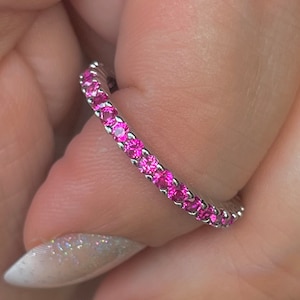 May include: A silver band ring with a row of pink gemstones.