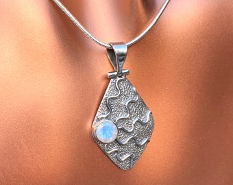 May include: A silver pendant necklace with a moonstone set in a textured, diamond-shaped design.