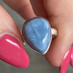 May include: A silver ring with a teardrop-shaped blue opal gemstone.