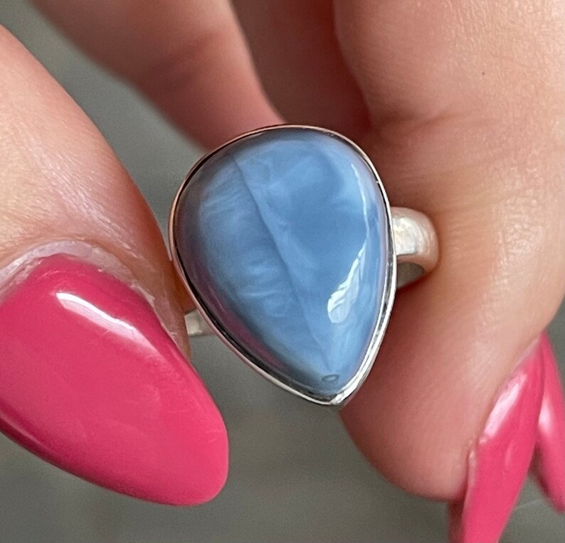 May include: A silver ring with a teardrop-shaped blue opal gemstone.