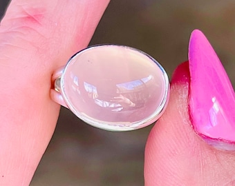 Puede incluir: Un anillo de plata con una gran piedra preciosa rosa translúcida de forma ovalada.