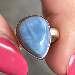 May include: A silver ring with a teardrop-shaped blue opal gemstone.
