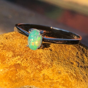 May include: A silver ring with a light green oval opal gemstone.