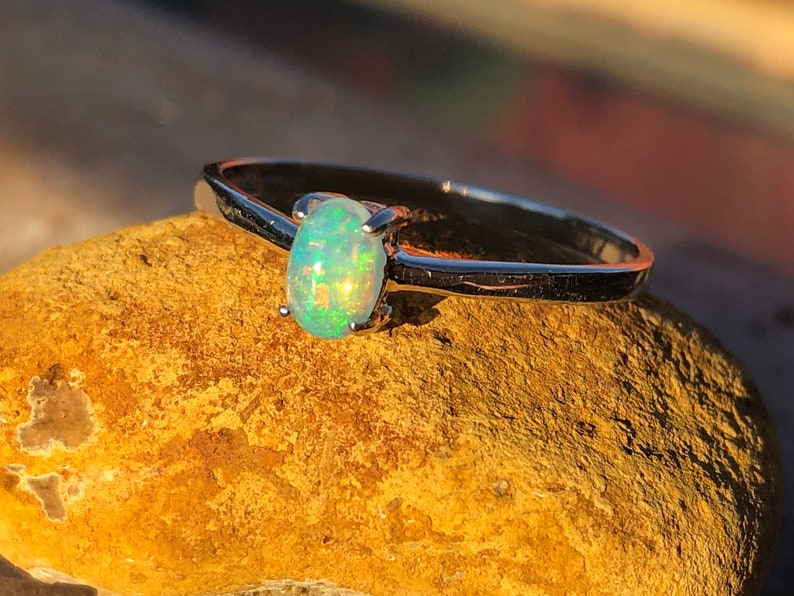 May include: A silver ring with a light green oval opal gemstone.