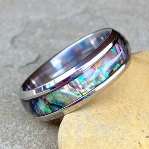 May include: A silver ring with a band of iridescent abalone shell inlay.