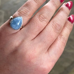 May include: A silver ring with a teardrop-shaped blue opal gemstone.