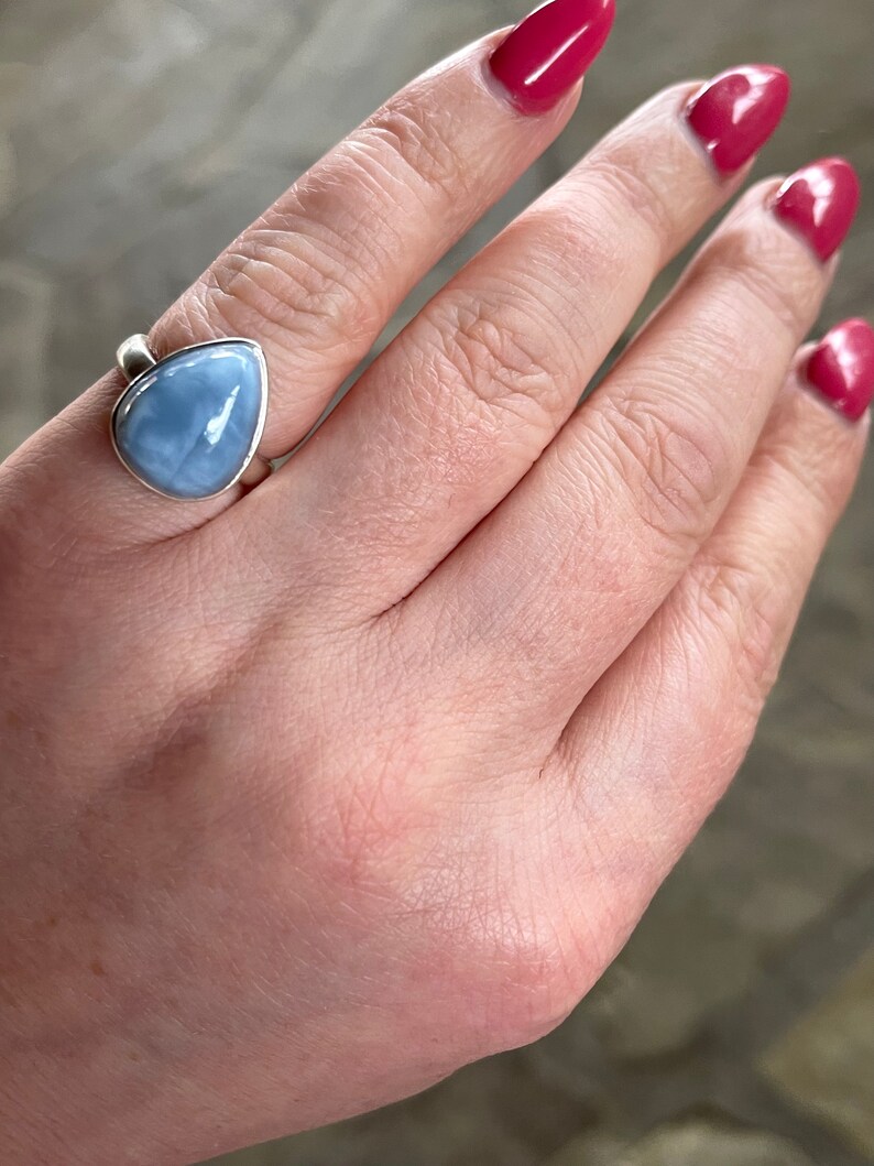 May include: A silver ring with a teardrop-shaped blue opal gemstone.