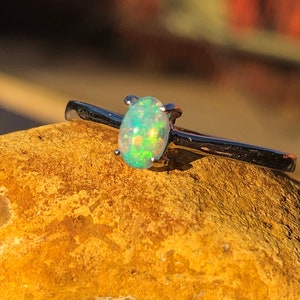 May include: A silver ring with a small oval opal gemstone. The opal is a light green color with flashes of rainbow.