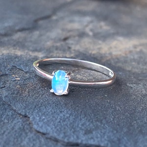 May include: A silver ring with a light blue oval gemstone.