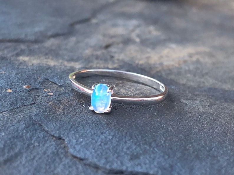 May include: A silver ring with a light blue oval gemstone.