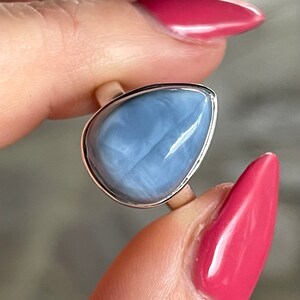 May include: A silver ring with a light blue teardrop-shaped opal gemstone.