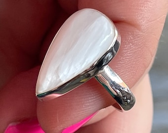 May include: A teardrop-shaped ring with a white mother-of-pearl stone set in a silver band.