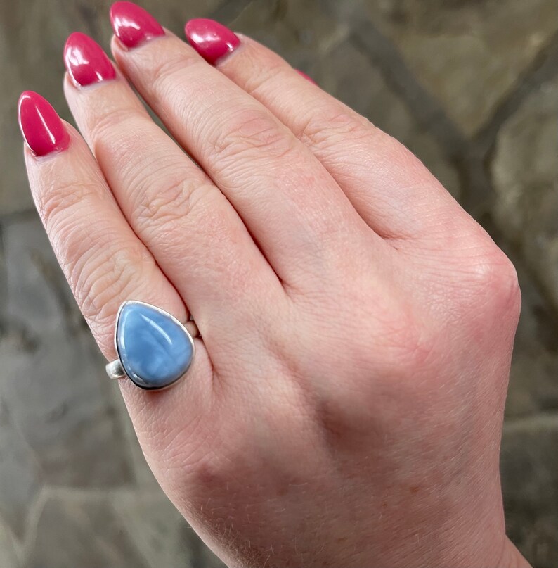 May include: A silver ring with a teardrop-shaped blue opal gemstone.