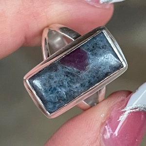 May include: A silver ring with a rectangular blue and pink gemstone set in a silver bezel.