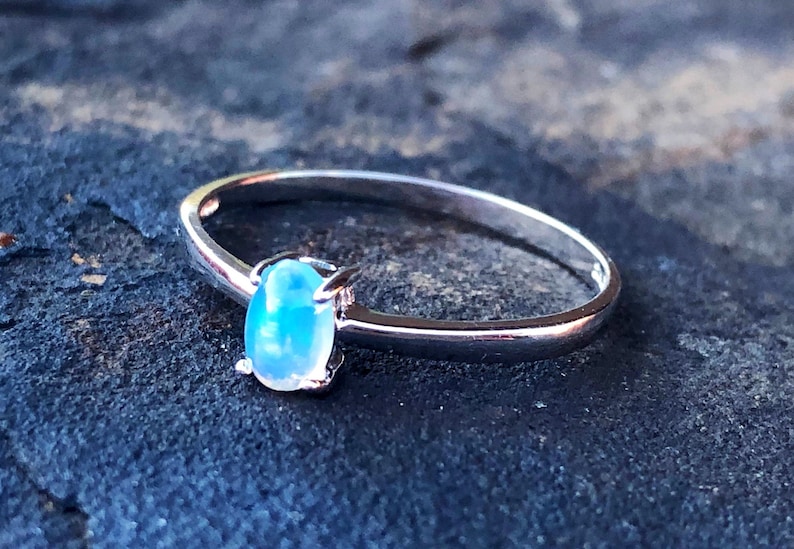 May include: A silver ring with a light blue oval opal gemstone.