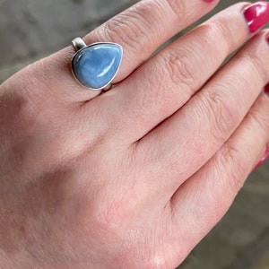 May include: A silver ring with a teardrop-shaped blue opal gemstone.