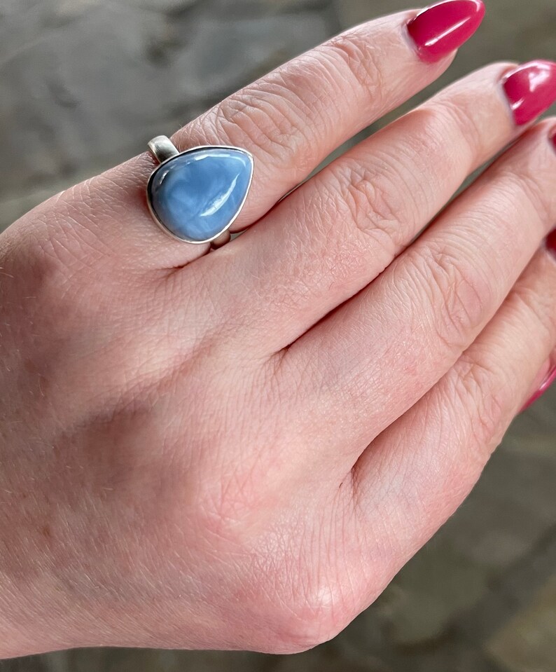 May include: A silver ring with a teardrop-shaped blue opal gemstone.