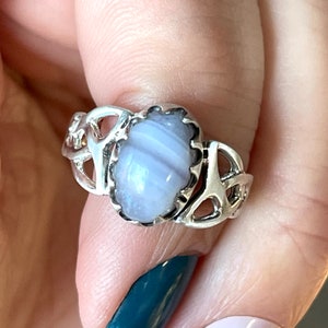 May include: A silver ring with a Celtic knot design and a light blue agate stone.