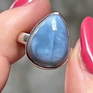 May include: A silver ring with a teardrop-shaped blue opal gemstone.