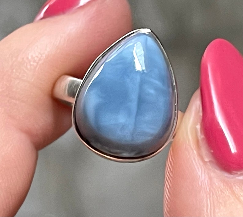 May include: A silver ring with a teardrop-shaped blue opal gemstone.