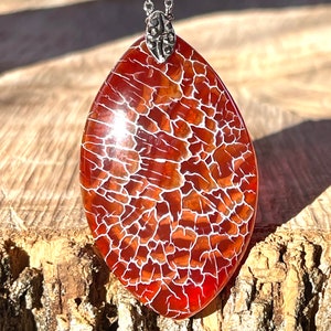 May include: A red and white agate pendant with a silver chain. The agate has a unique crackled pattern.