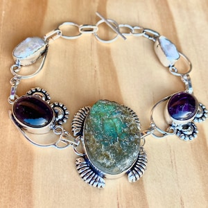 May include: A silver bracelet with a large green labradorite stone, two smaller amethyst stones, and two white pearl stones.