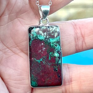 May include: A silver chain necklace with a rectangular pendant featuring a green and red jasper stone.
