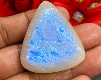 May include: A white opal cabochon with a triangular shape and a blue iridescent sheen.